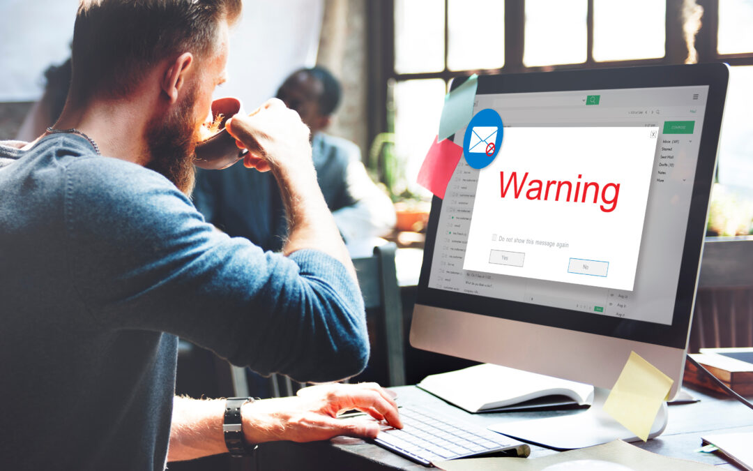 man sipping coffee in front of computer screen with warning pop-up